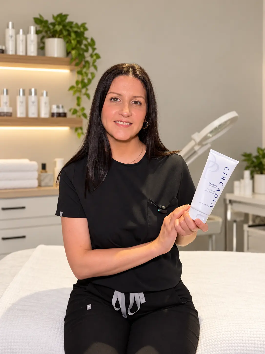 Jessica Rodriguez, licensed esthetician, in her treatment room with a Circadia product